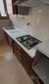 Cucina con piano cottura e frigo.
