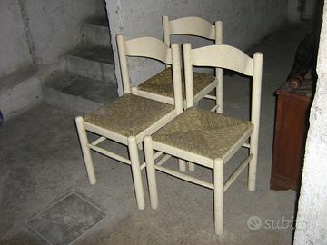 una sedia in paglia e tre sedie in legno