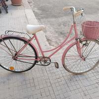 Bicicletta rosa con cestino e portapacchi