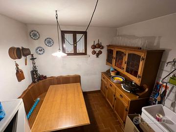 Tavolo, cassapanca, tre sedie e credenza alta. 