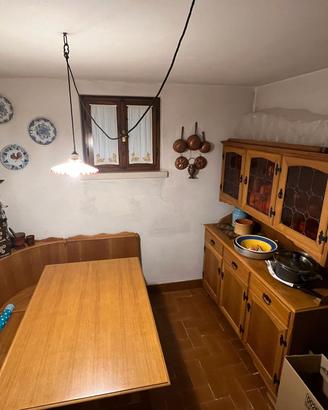 Tavolo, cassapanca, tre sedie e credenza alta.