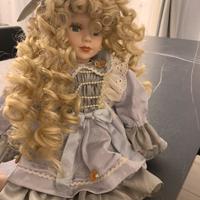 Bambola seduta con vestito azzurro