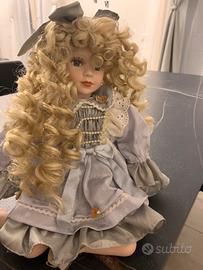 Bambola seduta con vestito azzurro