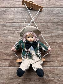 Bambolina in stoffa e ceramica su altalena