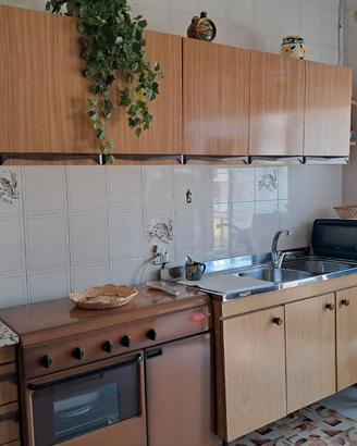 Mobili cucina con lavello, tavolo e sedie.