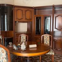 Salotto con tavolo e sedie e parete attrezzata