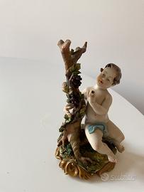 Statuetta in Capodimonte, putto seduto su un tronc