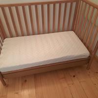 Lettino con sbarre in legno e materasso