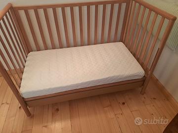 Lettino con sbarre in legno e materasso