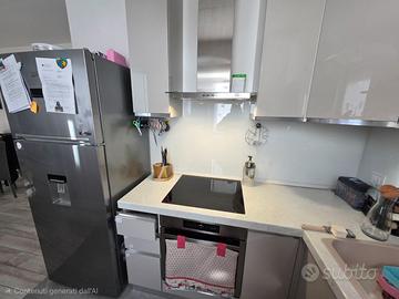 Cucina  angolare con elettrodomestici e frigo.