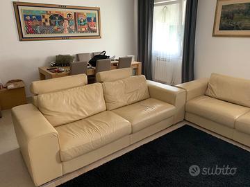 Coppia divani in pelle beige con puf