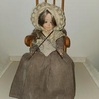 Bambola su sedia a dondolo vintage