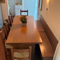 Tavolo in legno con due cassapanche e sei sedie
