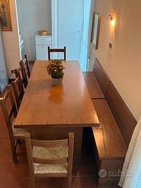 Tavolo in legno con due cassapanche e sei sedie