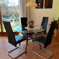 Tavolo rotondo in vetro con sedie nere