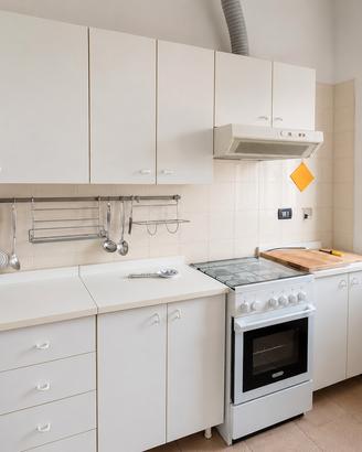 Cucina lineare bianca con fornelli e forno