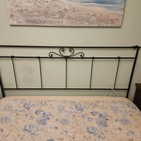 Letto matrimoniale, lampadario, lampade e tenda