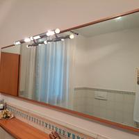 Specchio con cornice in ciliegio e lampada cromata