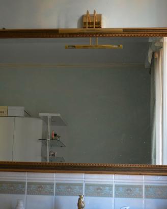 specchio con cornice pregiata dorata.