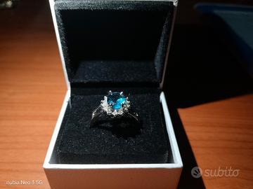 anello con pietra blu e circondato da zirconi