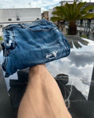 Jeans blu con strappi e macchie di pittura