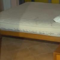 Letto matrimoniale in legno con rete a doghe.