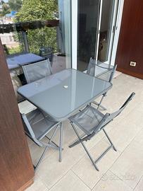Set tavolo grigio con ripiano in vetro e sedie