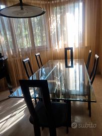 Tavolo di cristallo con sedie nere in pelle