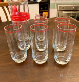 Bicchieri e brocca in vetro con bordo rosso