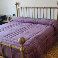 Letto matrimoniale e lampadario in ottone.