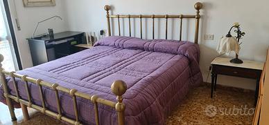 Letto matrimoniale e lampadario in ottone.