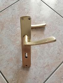 Maniglia dorata per porta con placca in alluminio.