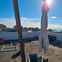 ampio ombrellone da terrazza con piefe in cemento.