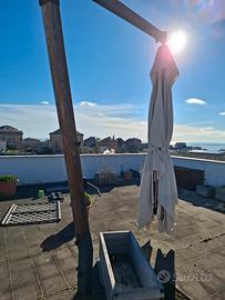 ampio ombrellone da terrazza con piefe in cemento.