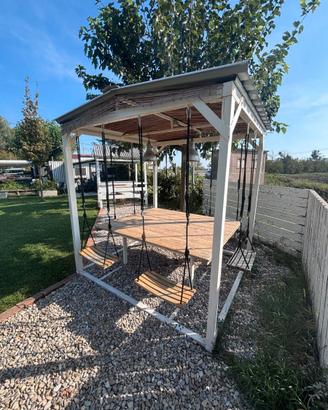 Gazebo da giardino con tavolo e sedie altalene.