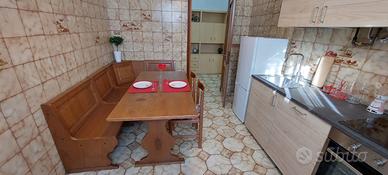 Cassapanca angolare e tavolo da cucina in legno.