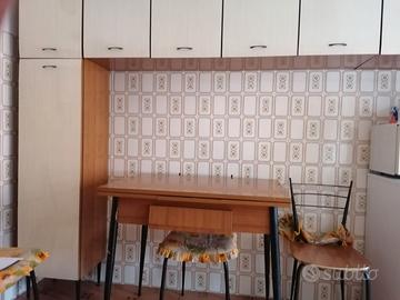 Cucina con pensili, tavolo e sedie