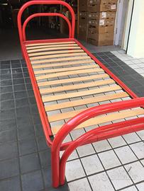 Letto rosso in ferro con rete a doghe