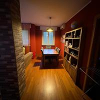 Sala da pranzo con tavolo e sedie, due divani.