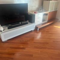 Parete attrezzata TV salotto poltrona e tavolino.