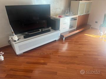 Parete attrezzata TV salotto poltrona e tavolino.