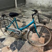 Bici da città azzurra con cesto e portapacchi