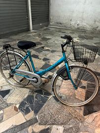 Bici da città azzurra con cesto e portapacchi