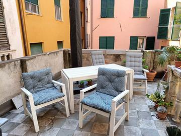 Tavolo in legno con sedie e cuscini da esterno