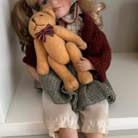 Bambola di porcellana seduta con orsetto