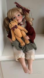 Bambola di porcellana seduta con orsetto