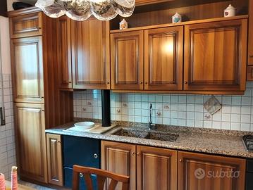 Cucina in noce completa di elettrodomestici.