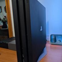Ps4 Pro con base verticale, cuffia e videogiochi.