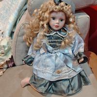 bambola in porcellana in posizione seduta