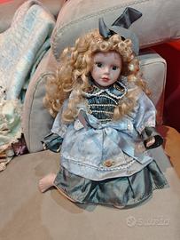 bambola in porcellana in posizione seduta